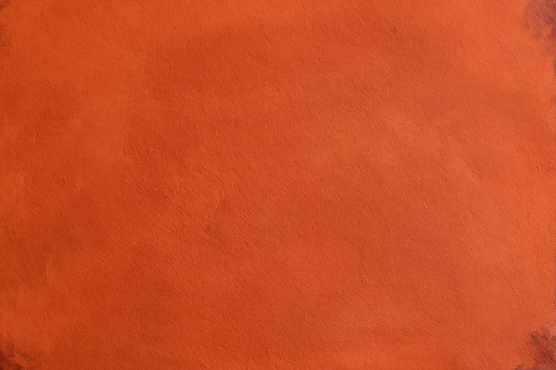 Close-up of an orange stucco plaster wall with textured surface
