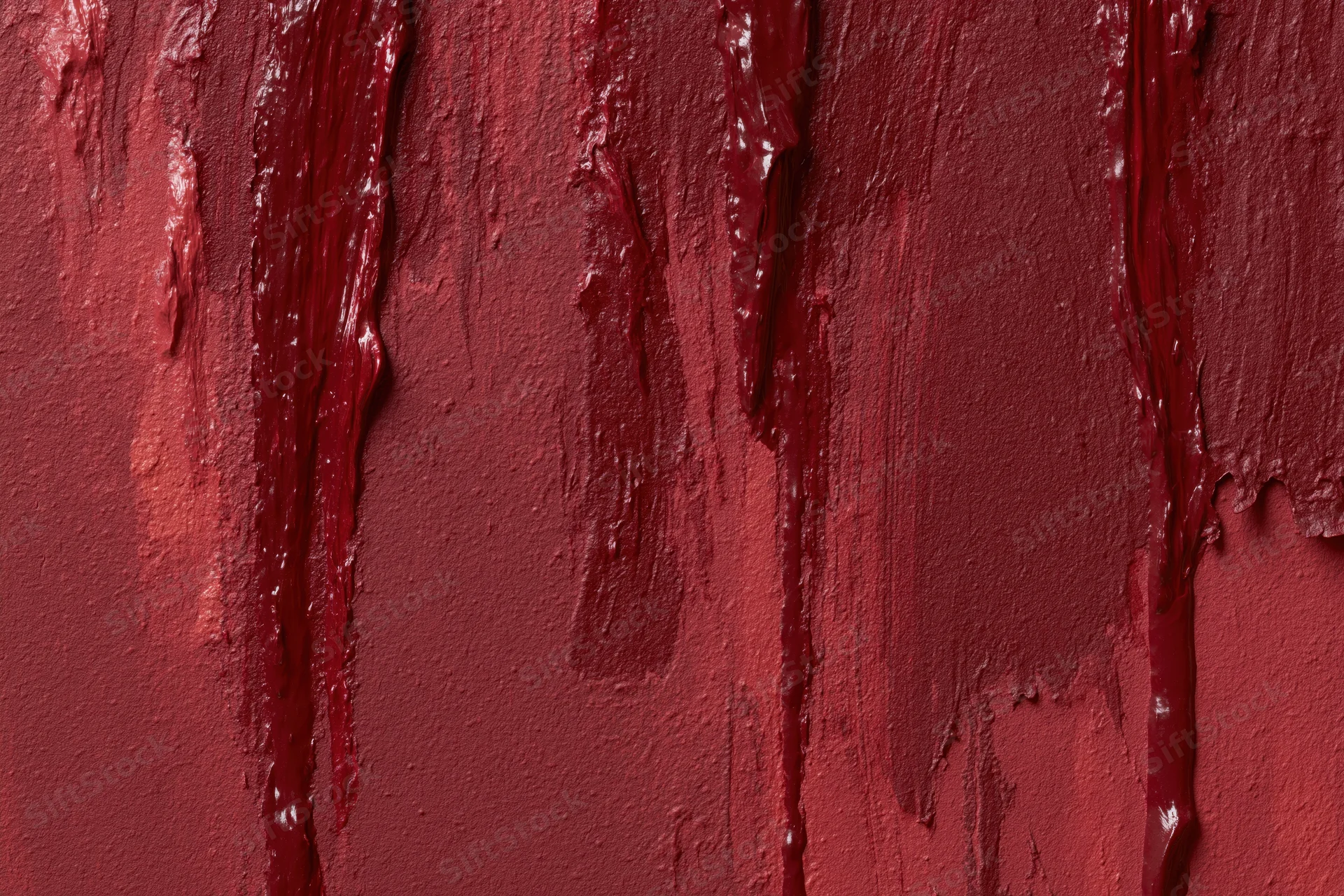Close-up of a rough painted wall surface with vertical red paint drips and textured finish