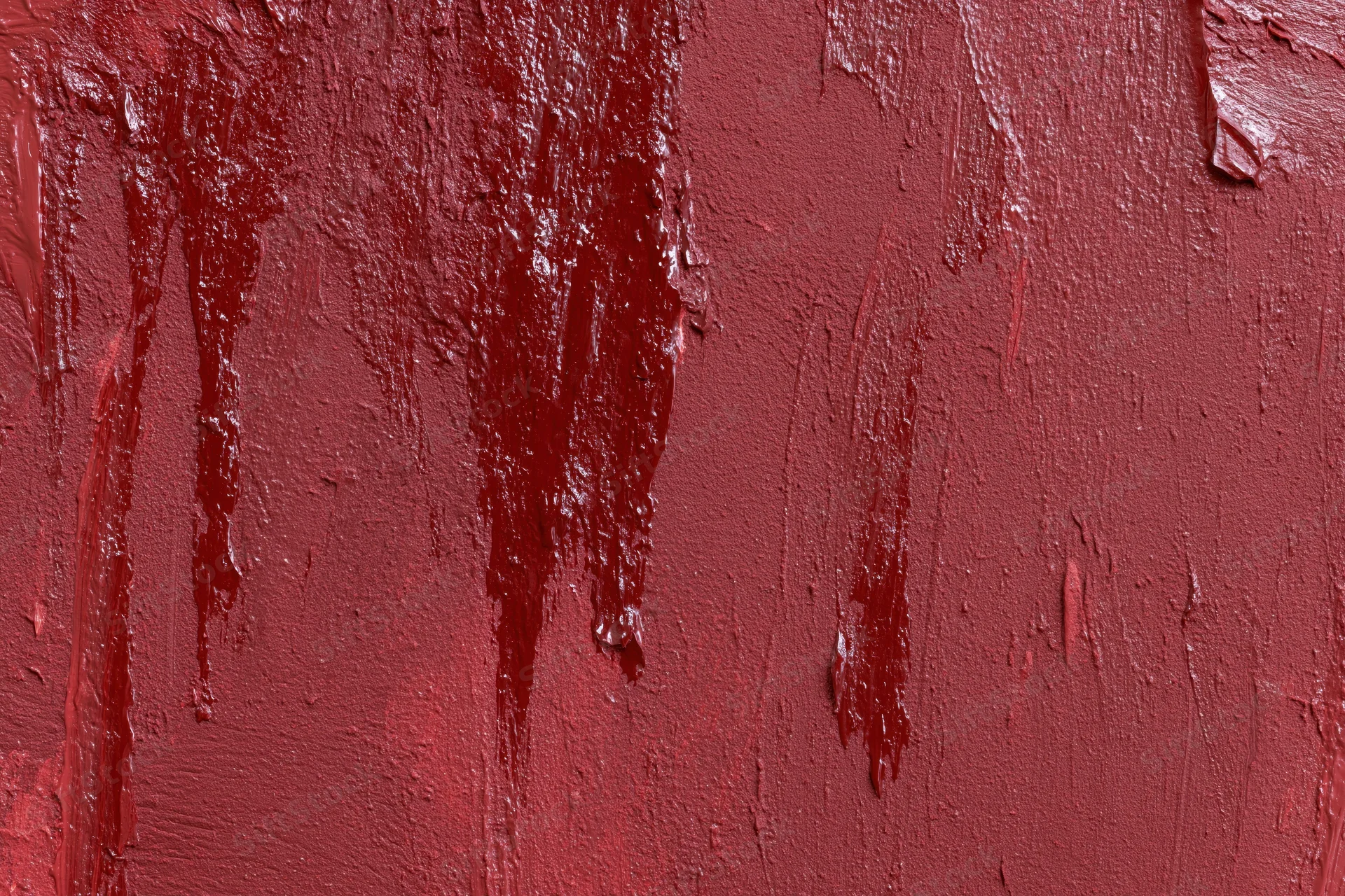 Close-up of a red painted wall with visible brushstrokes and drips showing texture and uneven coating