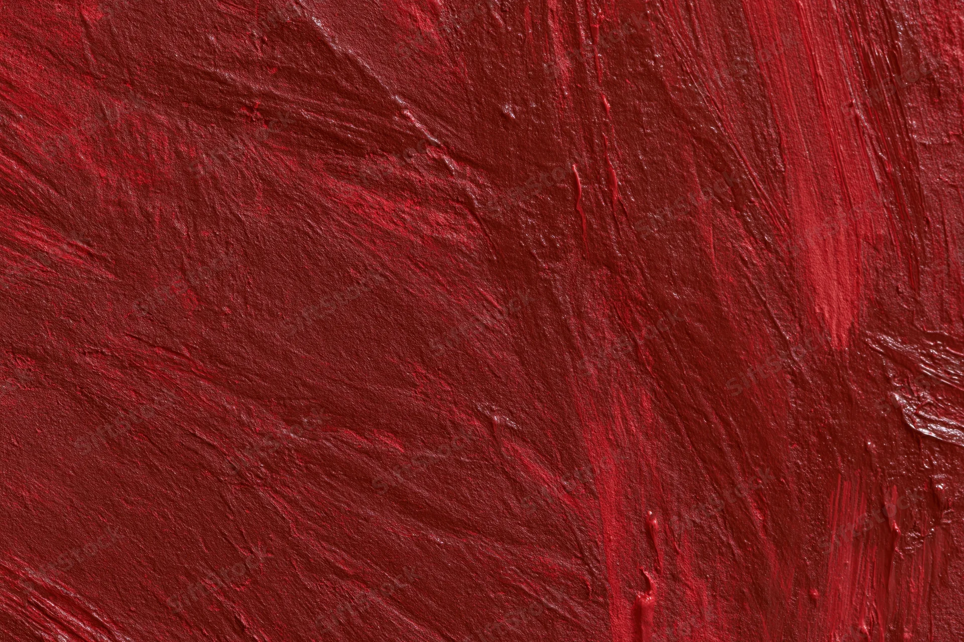 Close-up of a red painted wall surface with visible brushstrokes and texture