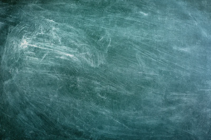 Worn green chalkboard surface with smudged white residue and scratches, showing texture and eraser marks