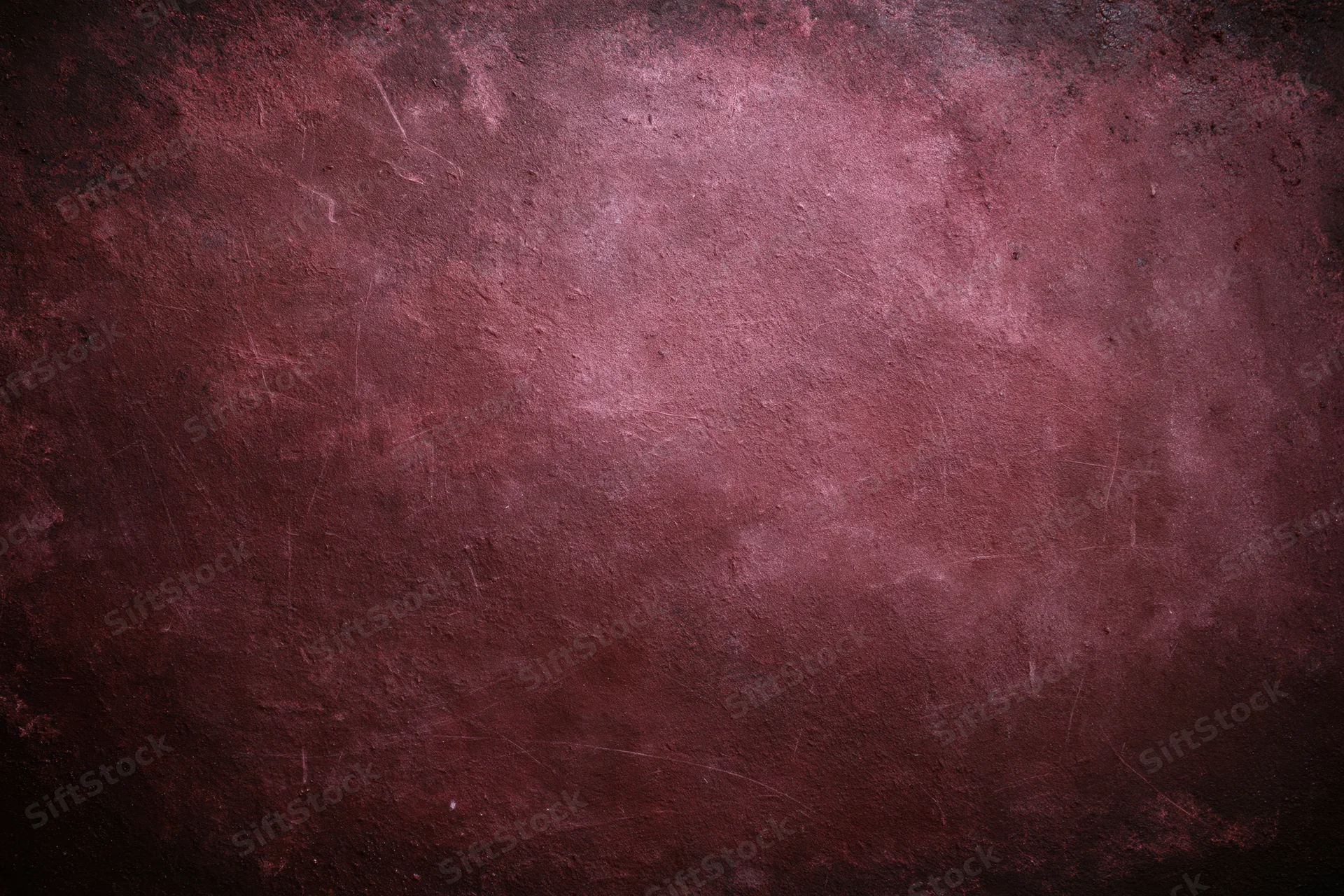 Close-up of an aged concrete wall surface with textured, weathered, and scratched details in dark red and maroon tones