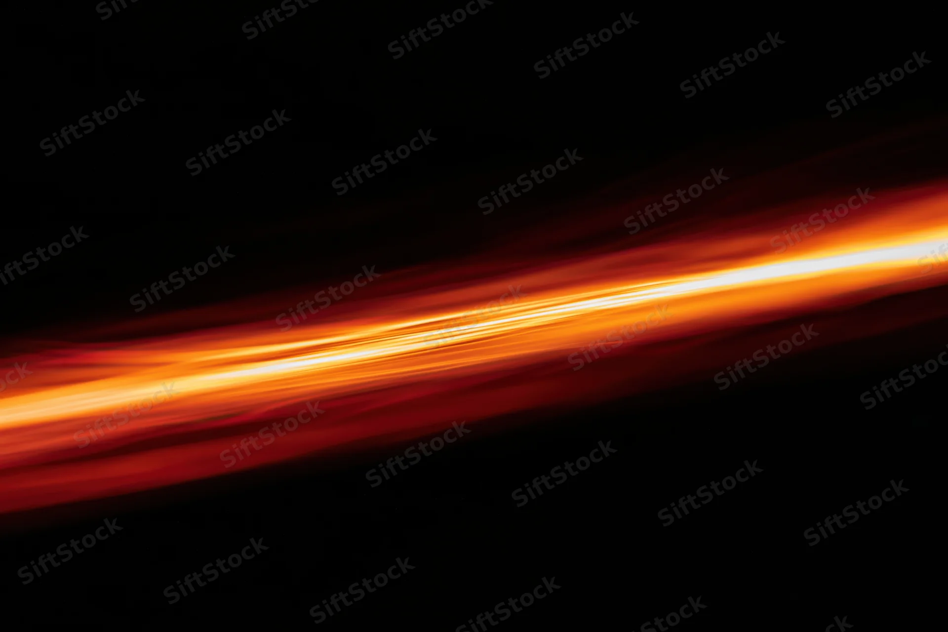 Long-exposure streak of molten light moving diagonally across dark background