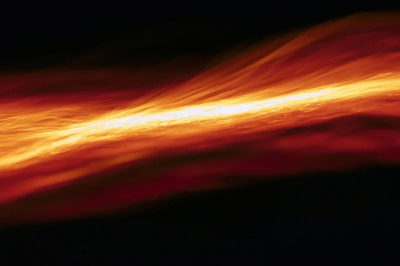 Molten light streaks flowing across dark space in long-exposure shot
