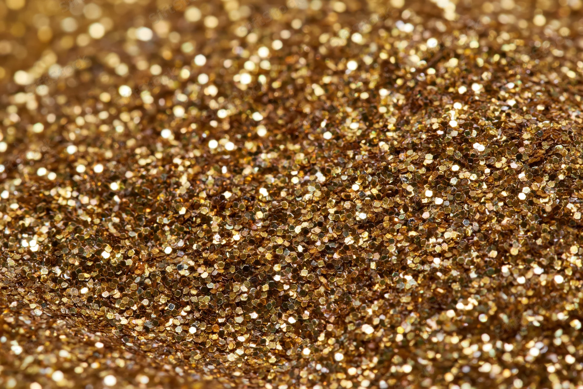 Dense gold glitter particles covering a surface in a close-up macro view