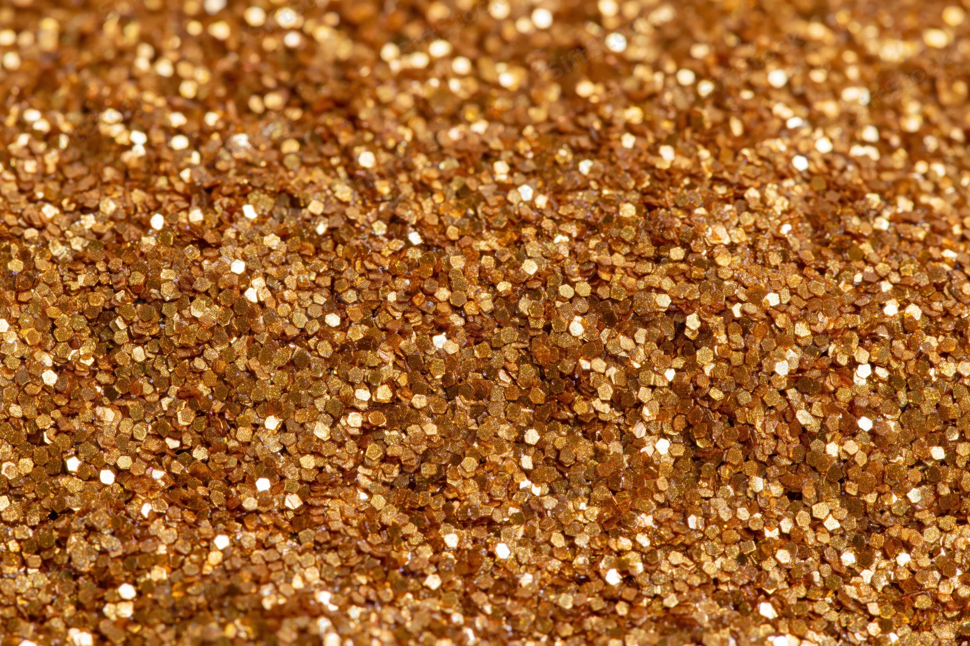 Dense gold glitter particles covering a surface in a close-up macro view