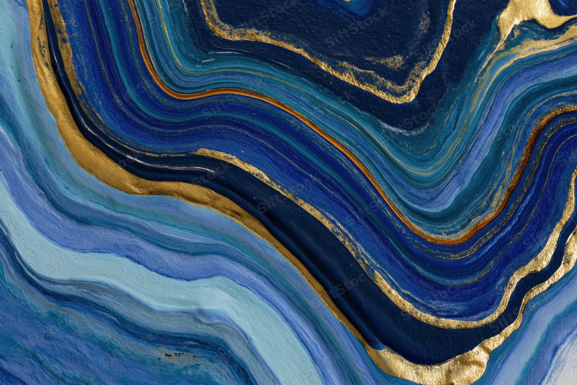 Fluid acrylic pour painting with swirling blue and gold layers on canvas