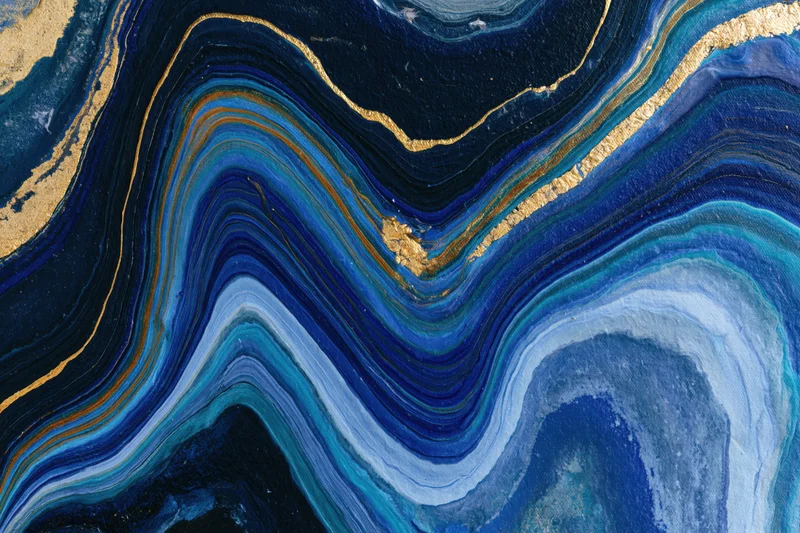 Fluid acrylic pour painting with swirling blue and gold layers on canvas