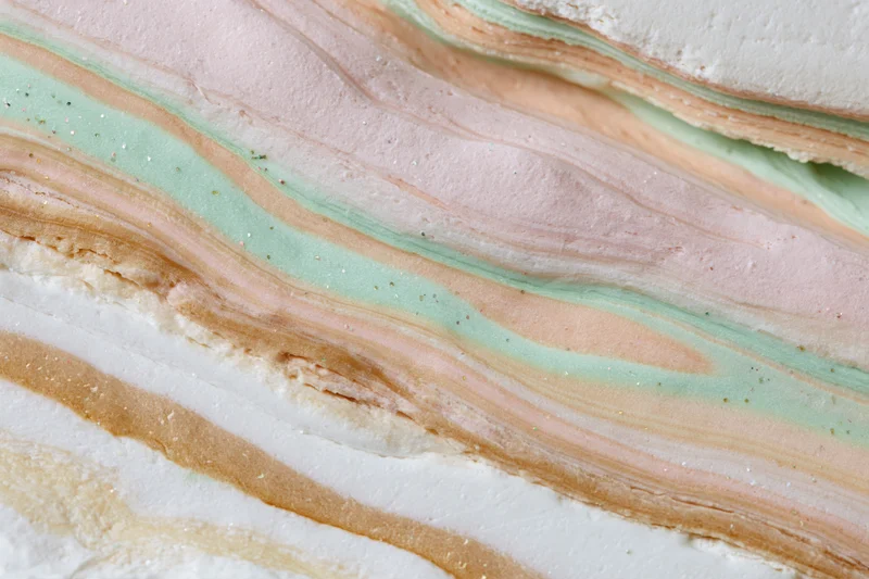 Swirling layers of pastel-colored liquid paint forming a marbled texture in close-up view