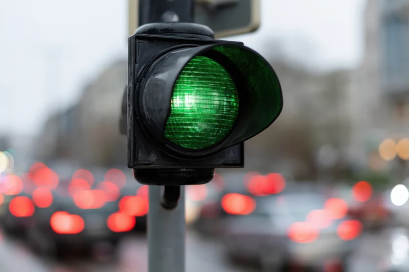 Green traffic light illuminated on city street with blurred vehicles in background