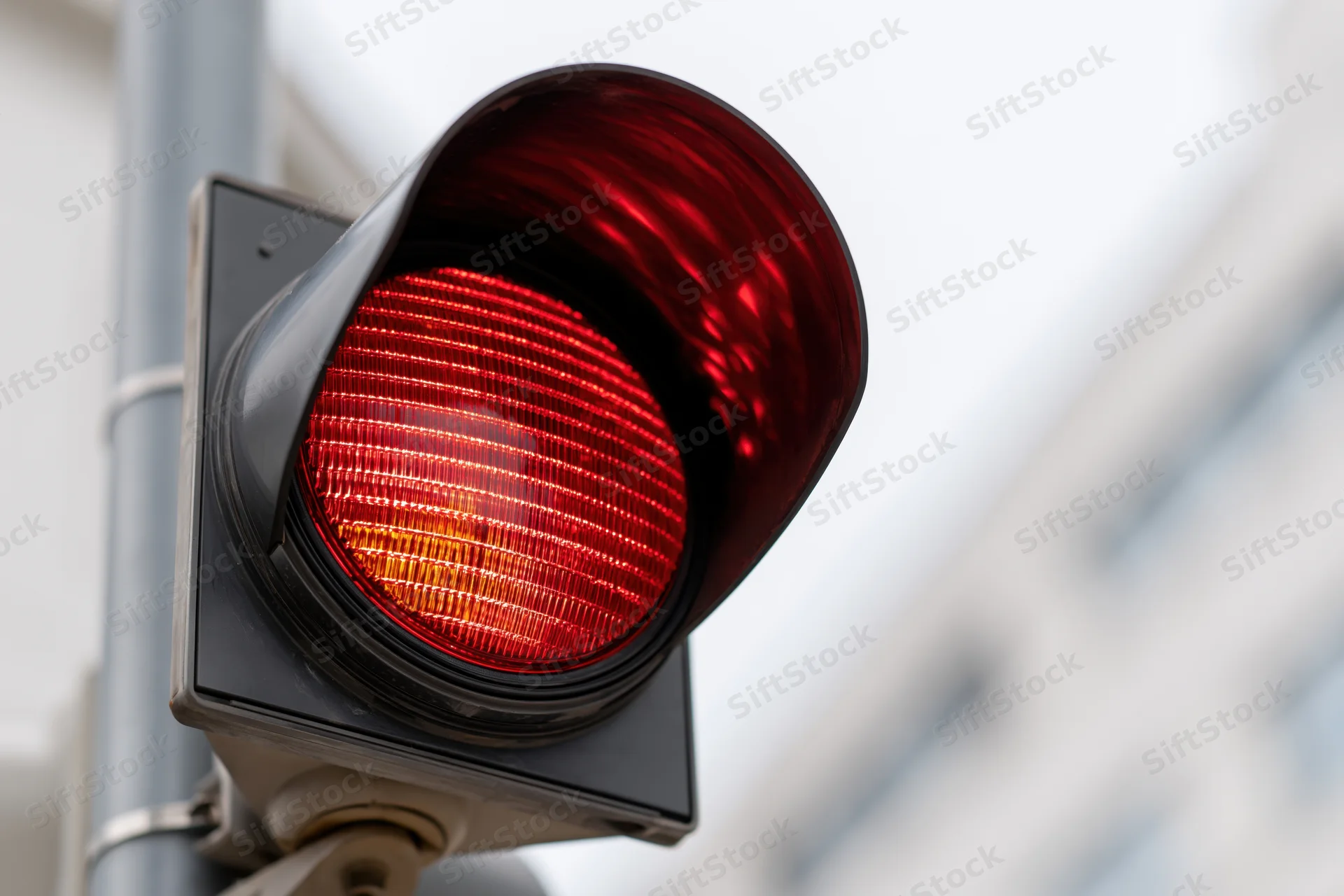 Glowing red traffic light signal mounted on a pole in an urban setting