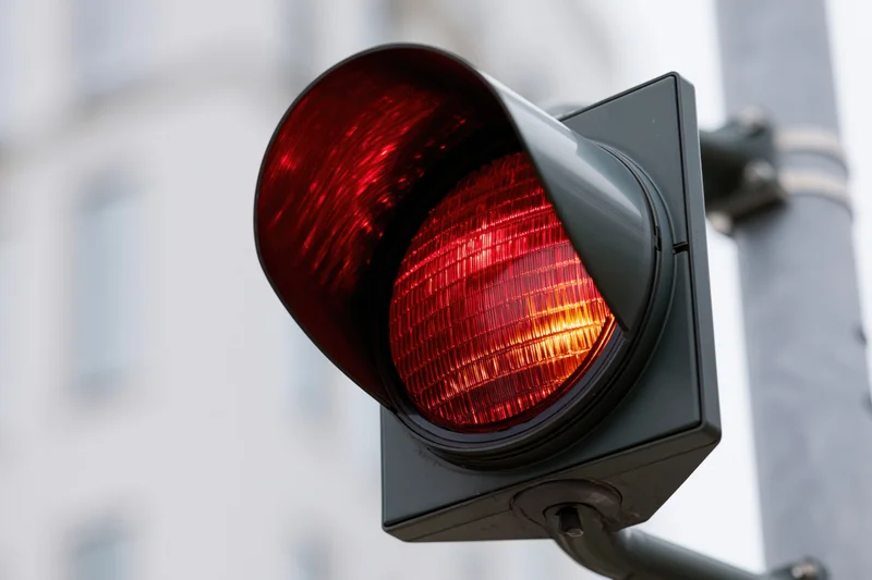 Glowing red traffic light signal mounted on a pole in an urban setting