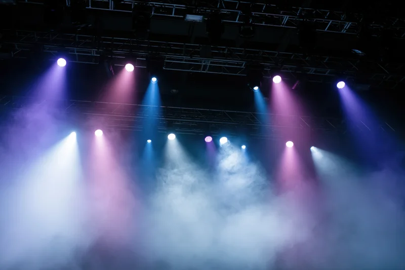 Stage lighting rig with colorful spotlights and smoke below the truss structure