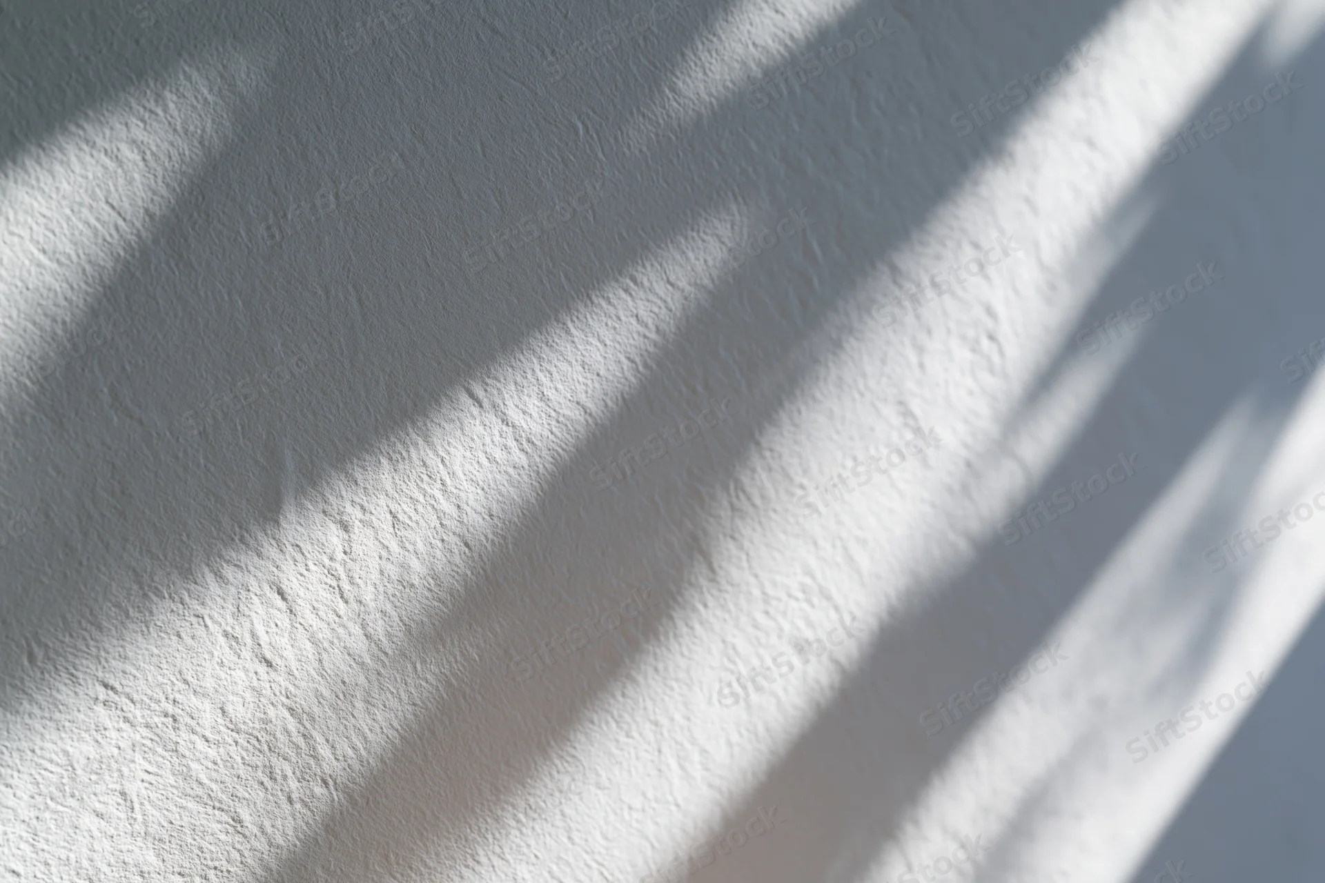 Dappled natural light casting soft diagonal shadows across a textured white wall interior