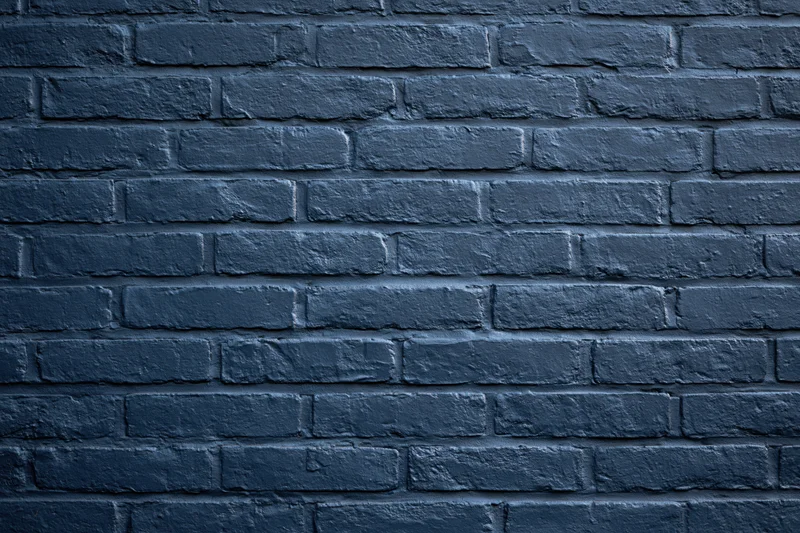 Navy-painted brick wall filling the frame flat-on as a textured background
