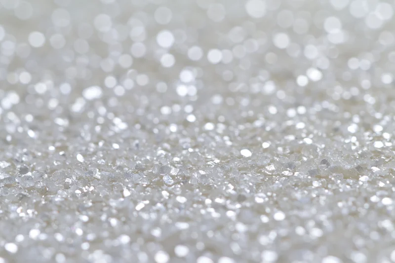 Defocused white and silver light orbs scattered across a sparkling surface as a background
