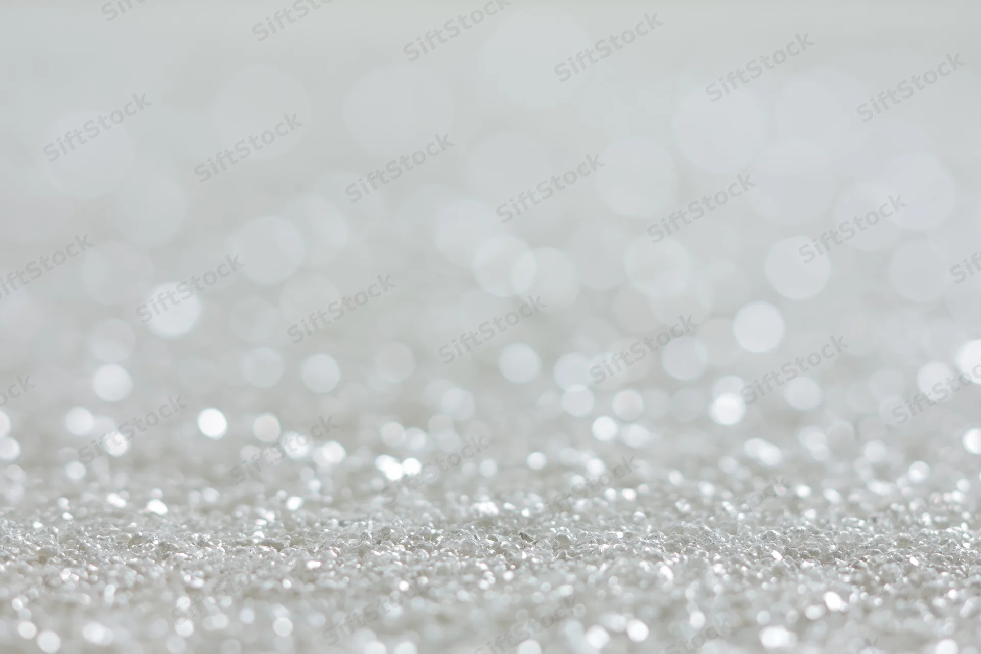 Silver glitter texture with blurred light orbs in foreground