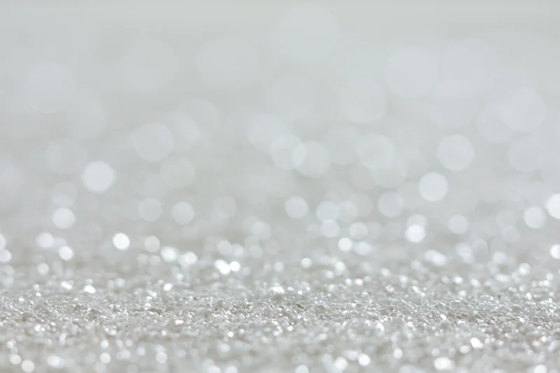 Silver glitter texture with blurred light orbs in foreground