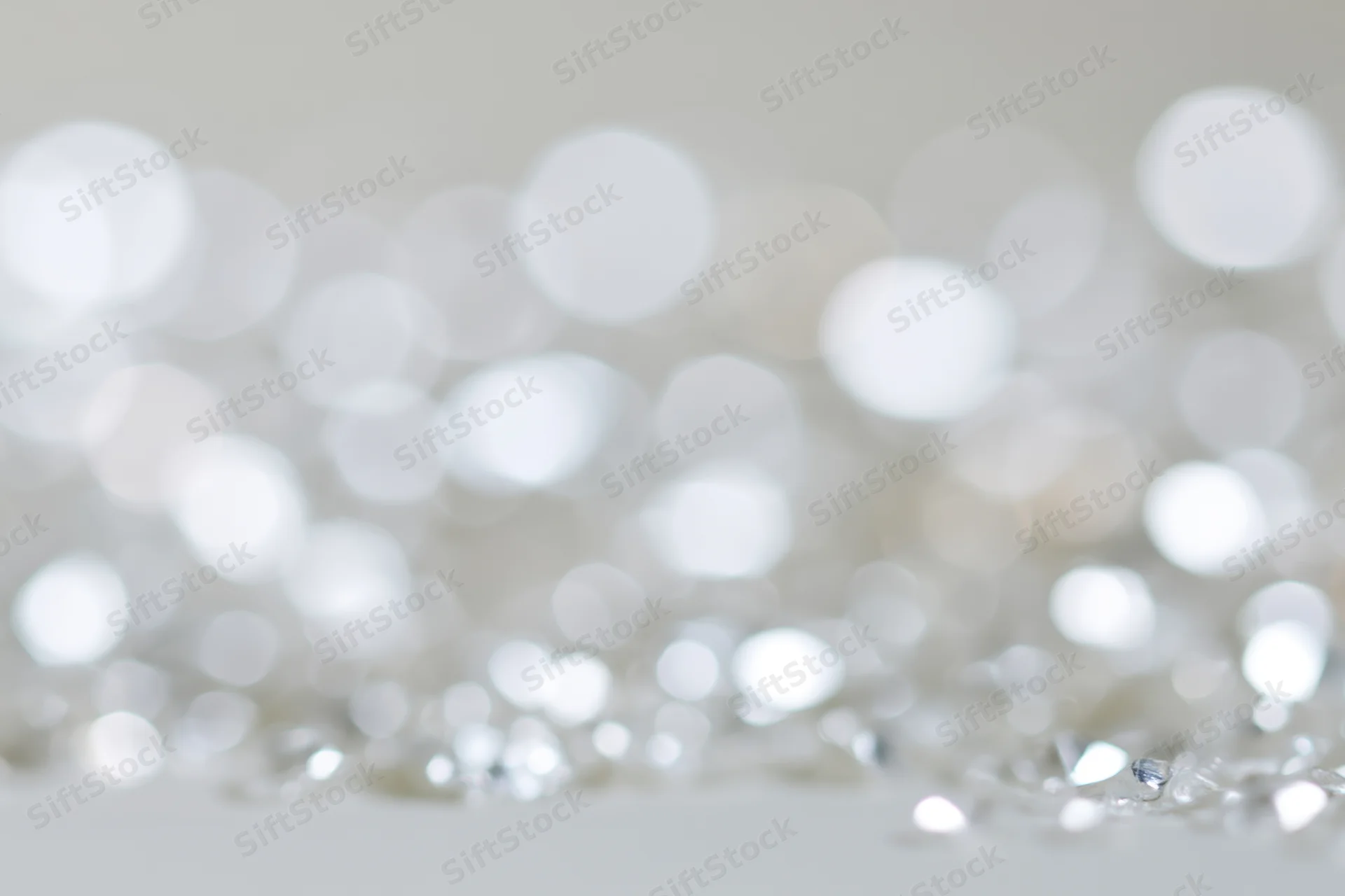 Scattered silver and white light orbs with bokeh effect on a soft background