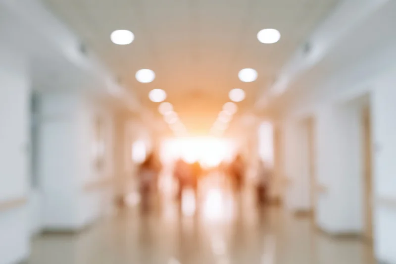 Defocused hospital corridor with blurred lights and doors receding into warm glow