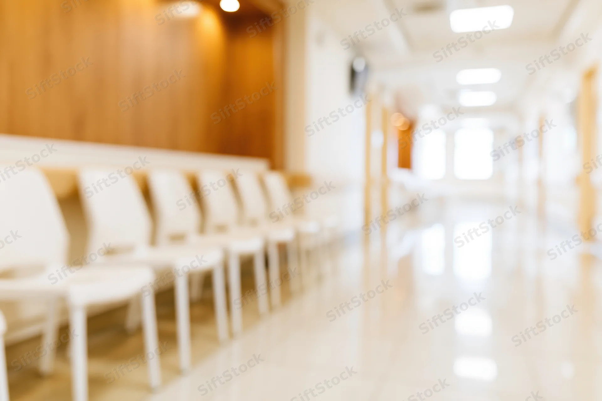 Row of white chairs along a defocused hospital corridor interior