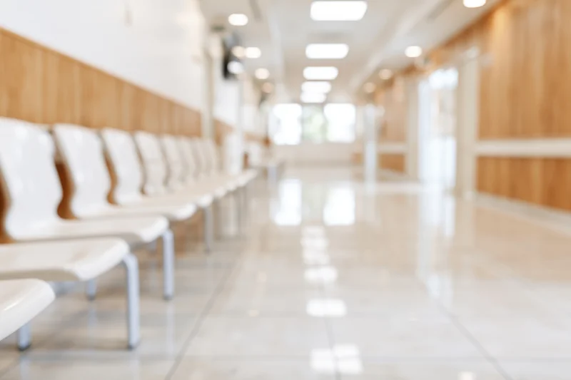 Row of white chairs along a defocused hospital corridor interior