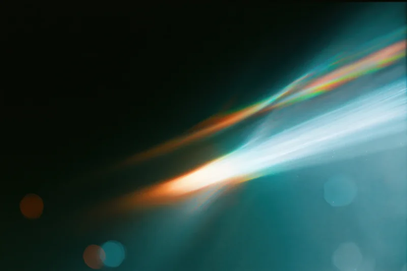 Defocused lens flare with colorful light streaks and bokeh against dark background