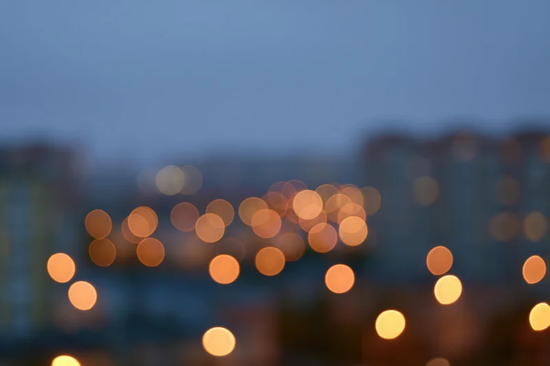 Blurred city lights at dusk with warm bokeh glow over apartment buildings