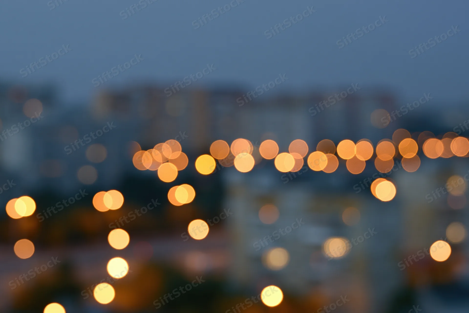 Blurred city lights at dusk with warm bokeh glow over urban apartment buildings