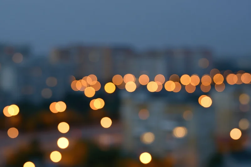 Blurred city lights at dusk with warm bokeh glow over urban apartment buildings