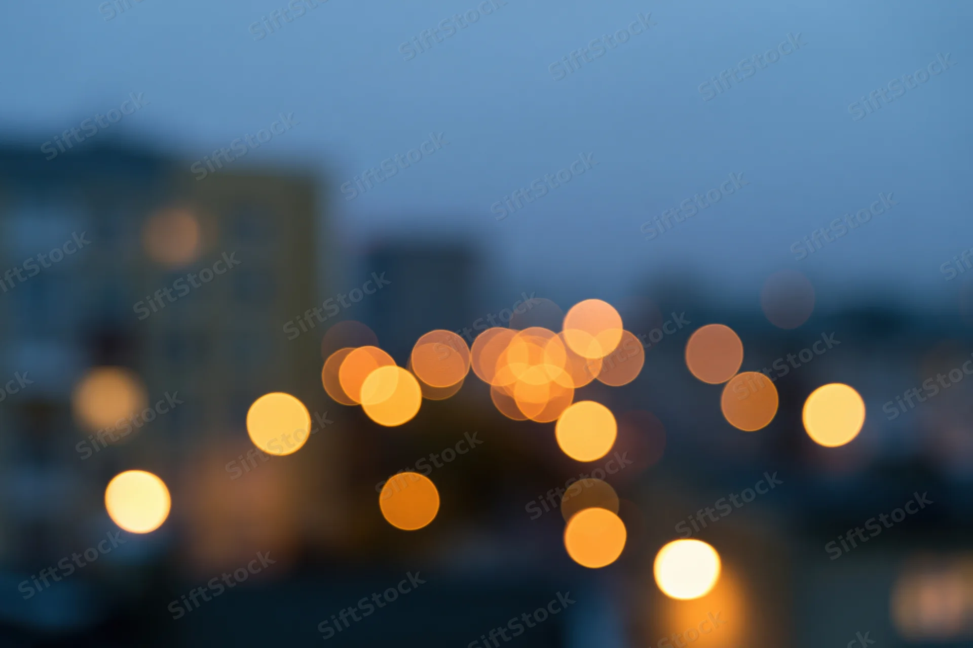 Blurred city lights at dusk with warm bokeh glow over urban apartment buildings