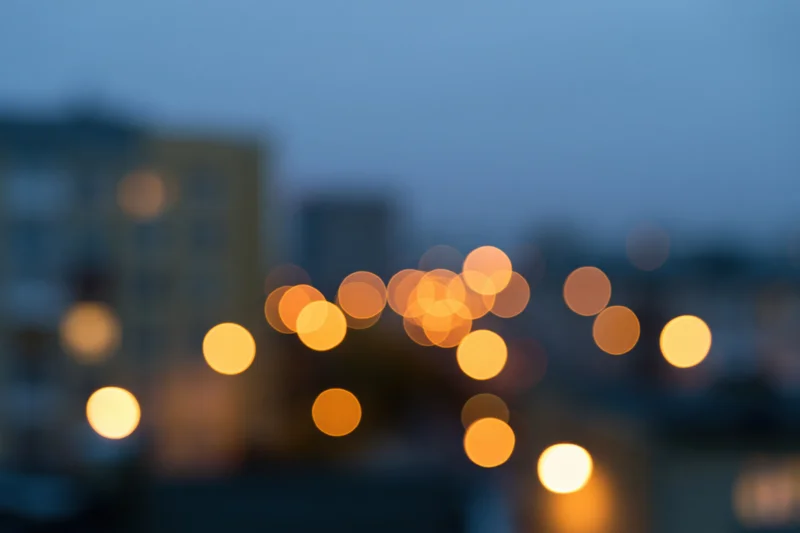 Blurred city lights at dusk with warm bokeh glow over urban apartment buildings