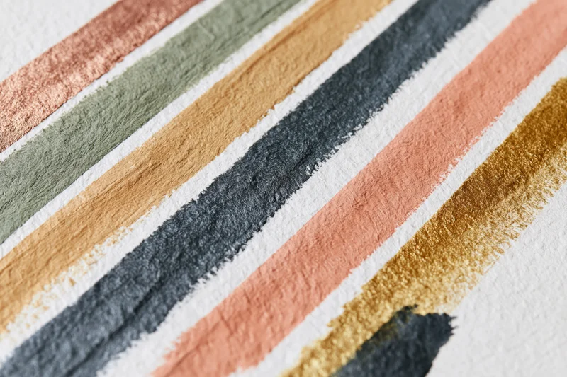 Diagonal paint brushstrokes in earthy tones on textured white paper