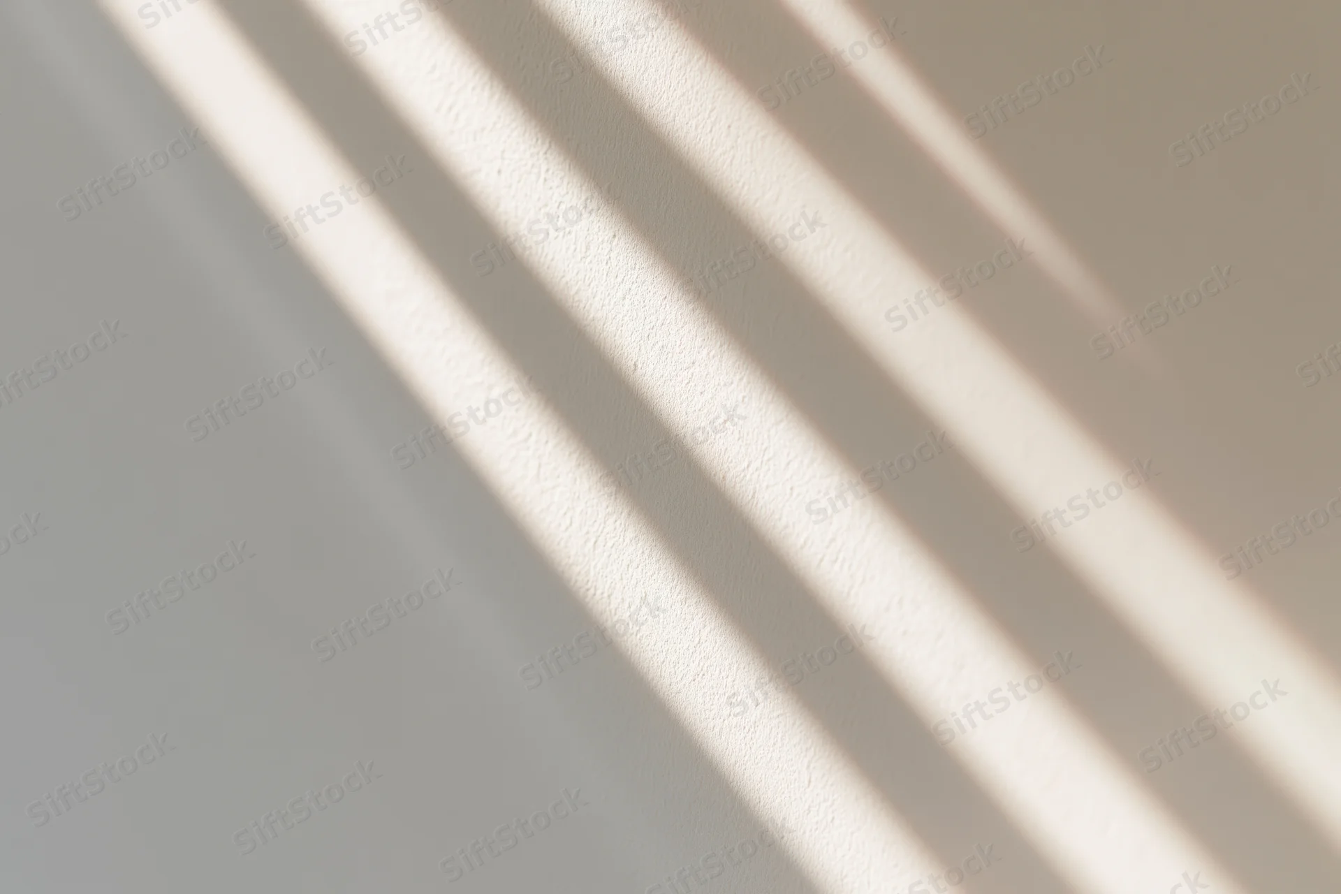 Diagonal stripes of sunlight and shadow cast across a plain wall indoors