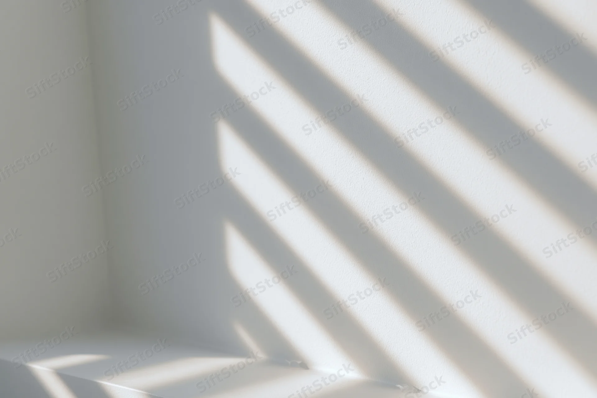 Diagonal light and shadow stripes cast across a white interior wall corner