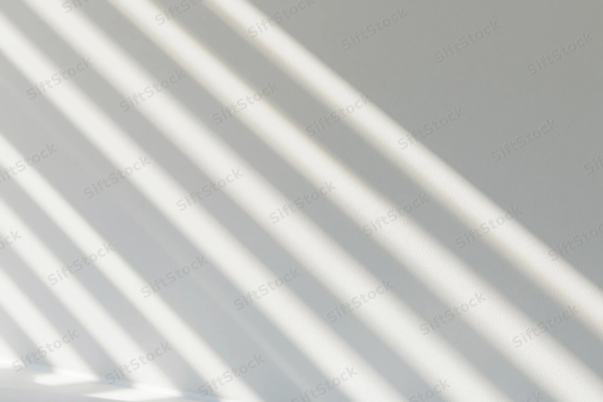 Diagonal stripes of sunlight and shadow cast across a white interior wall