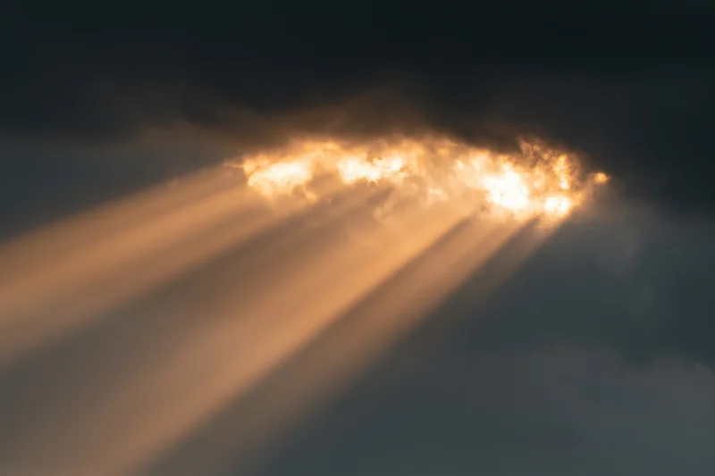 Golden sunlight beams breaking through dark clouds in the sky