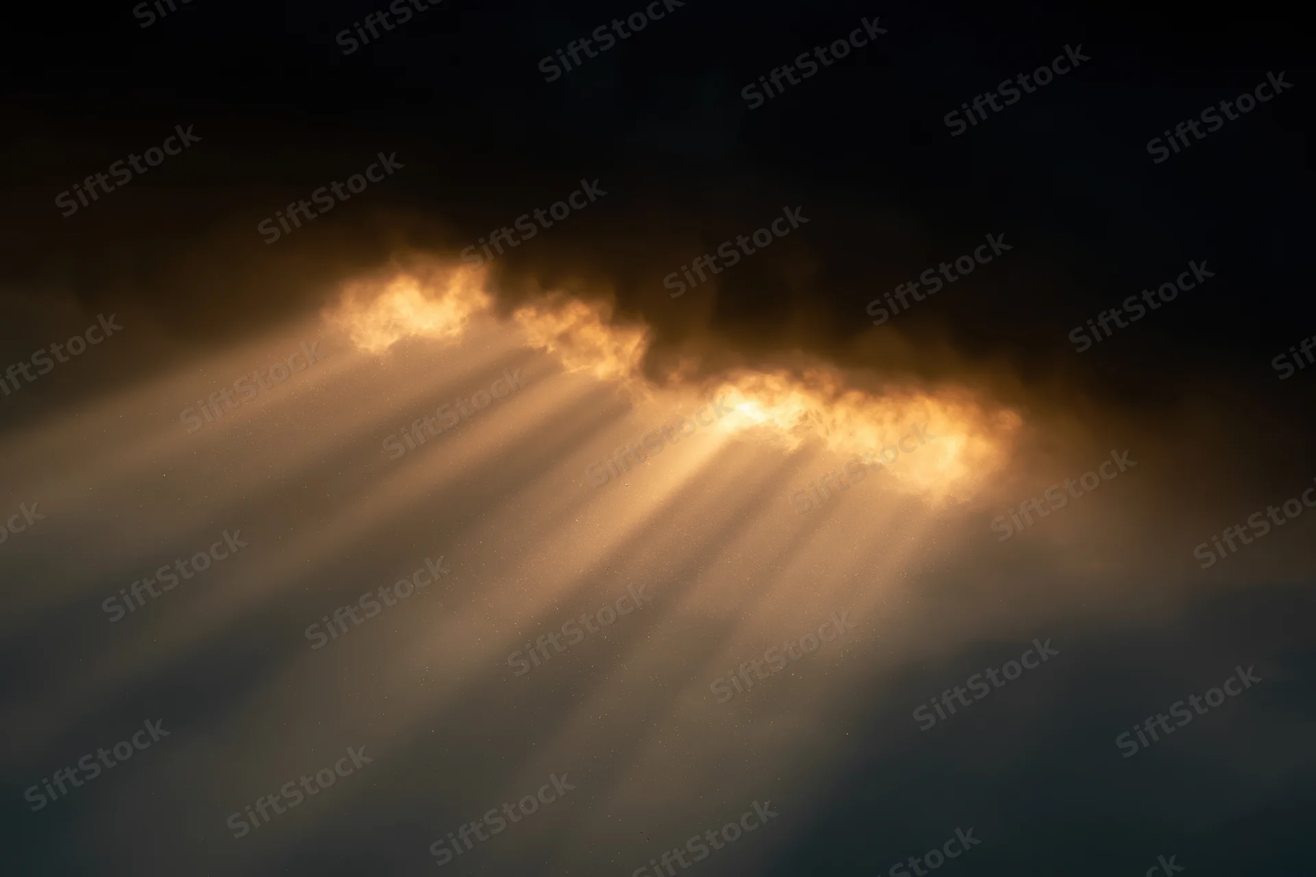 Golden sunlight beams breaking through dark clouds in the sky