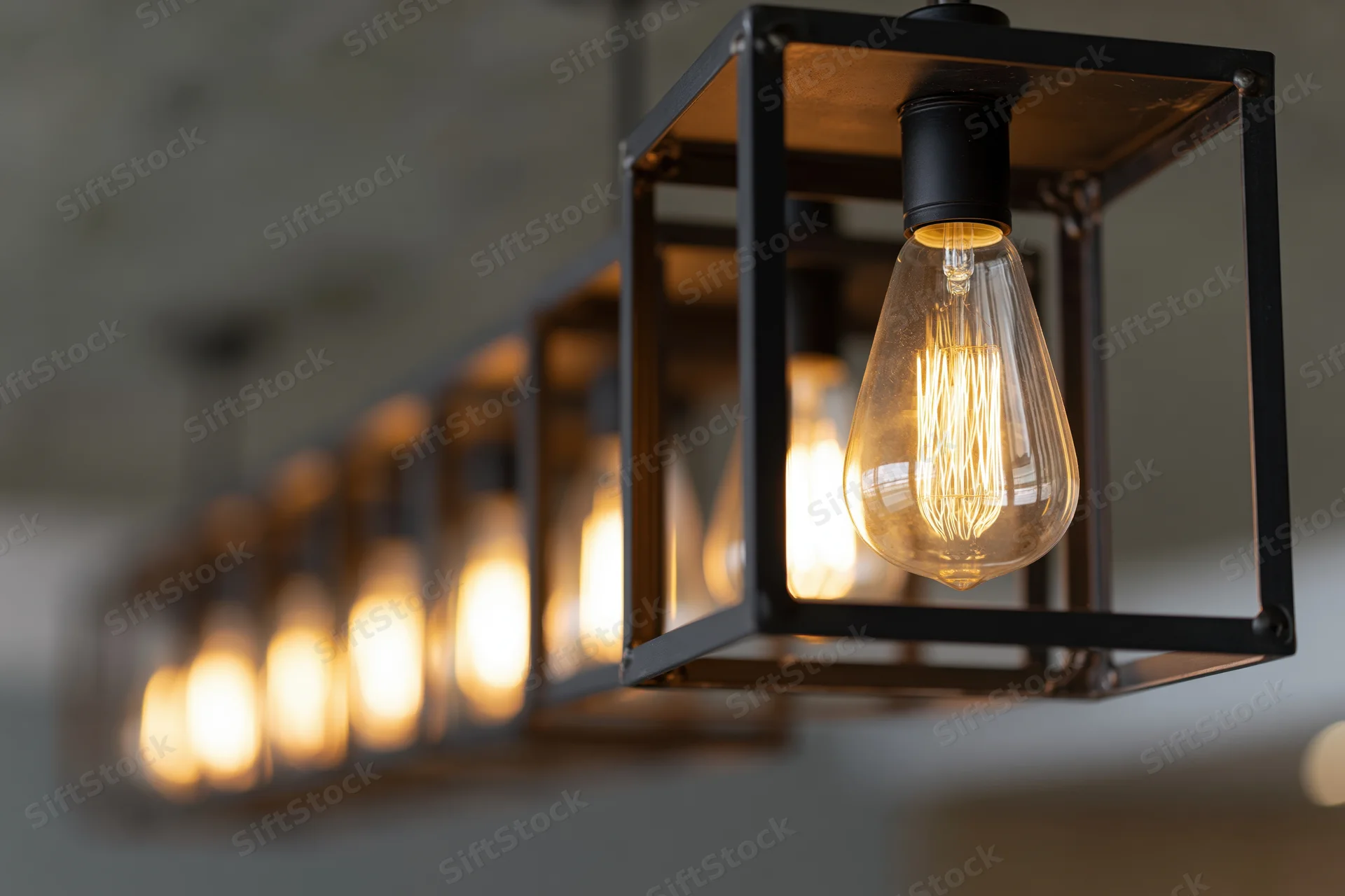 Edison filament bulbs suspended in open black metal cubes hanging from ceiling in linear row