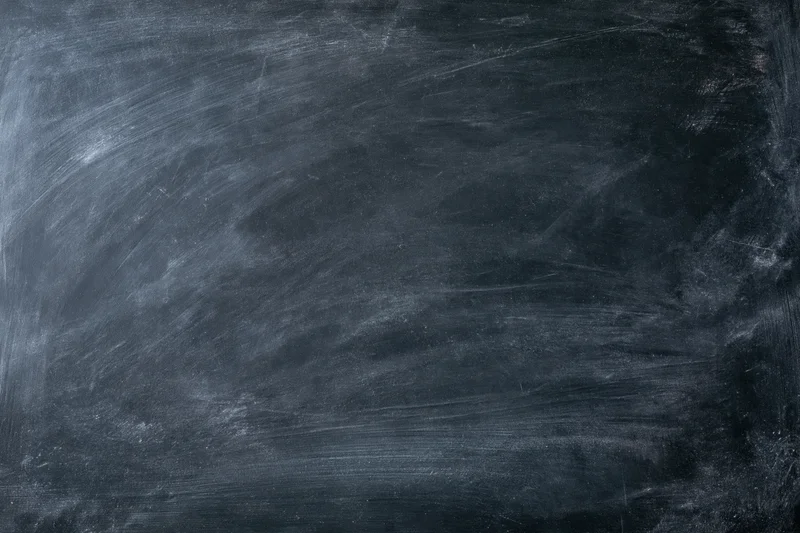 Empty blackboard surface filling the frame with chalk residue and smudges