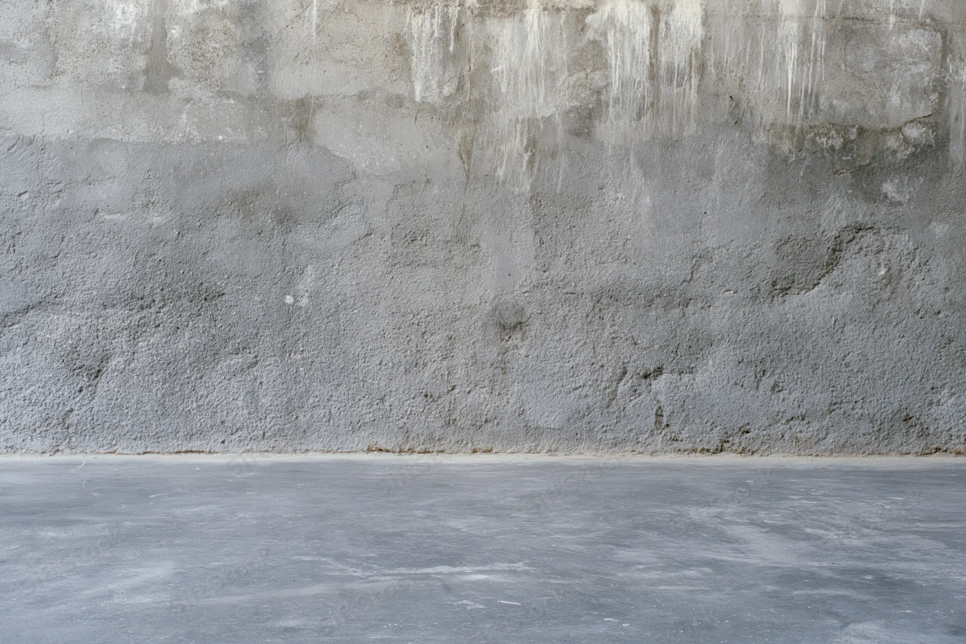 Empty concrete room interior with weathered cement wall and floor meeting at base