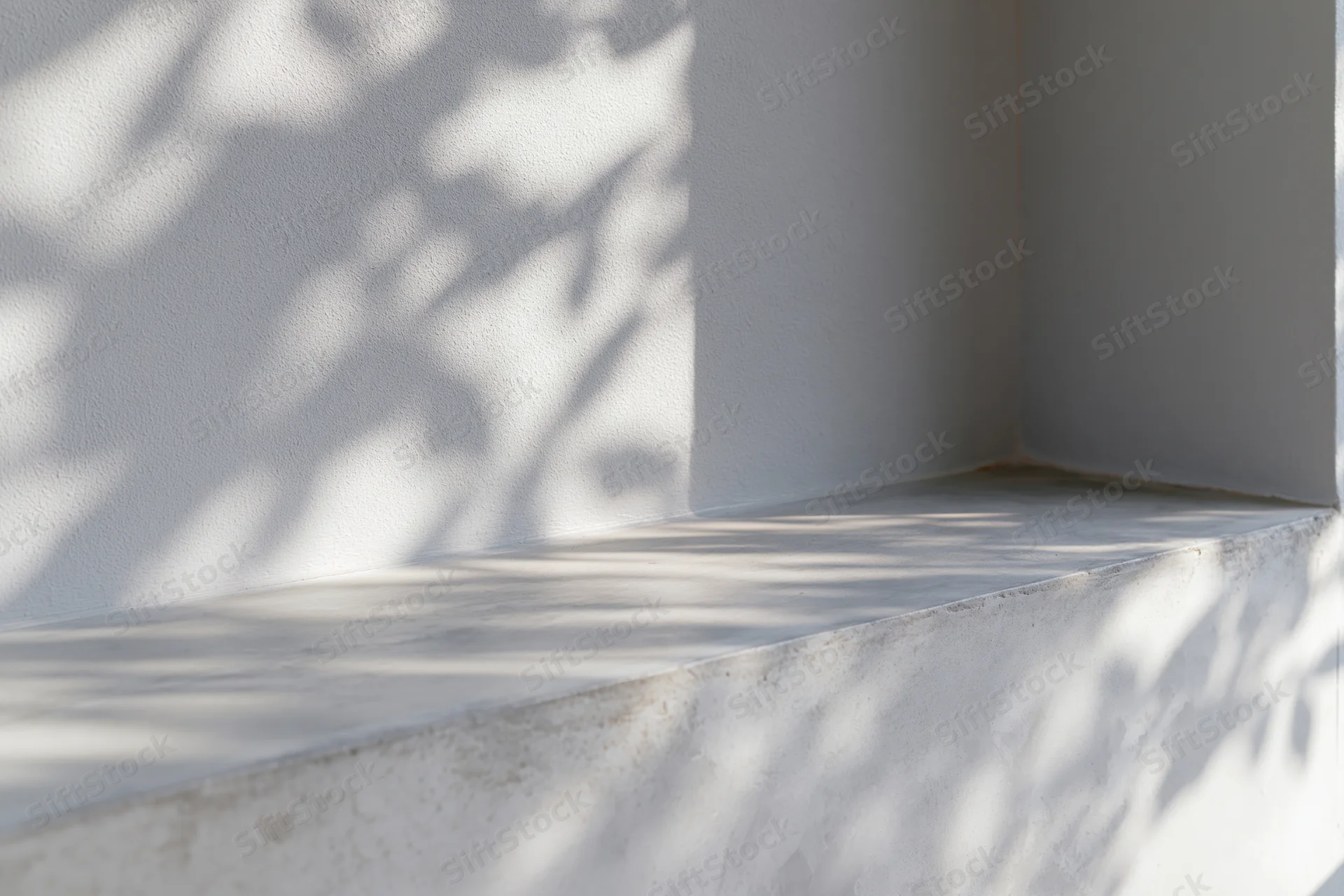 Dappled sunlight on a concrete ledge and gray wall corner outdoors