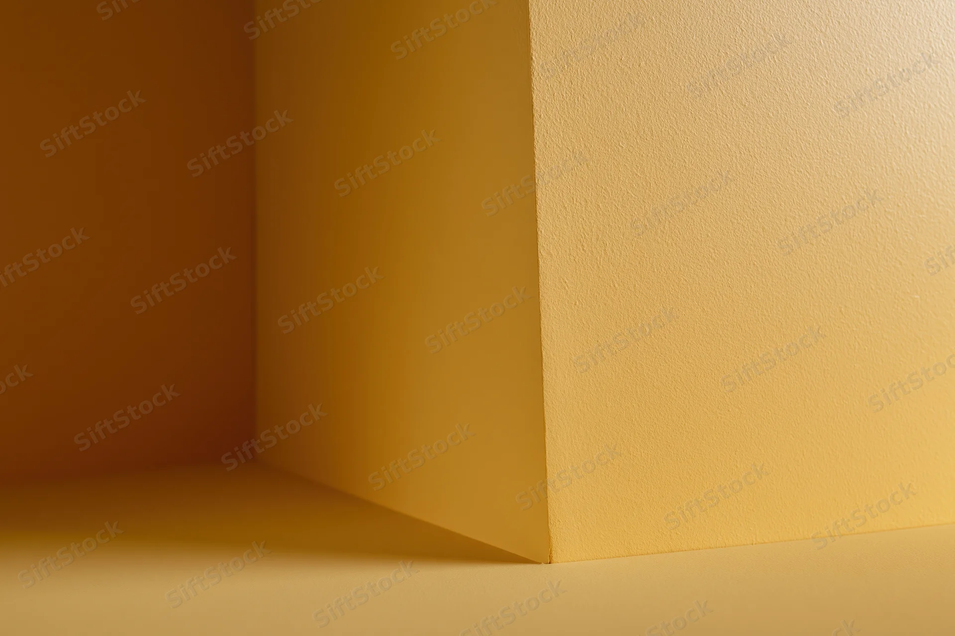 Empty corner of a room with golden yellow painted walls and floor, showing shadow and light gradient