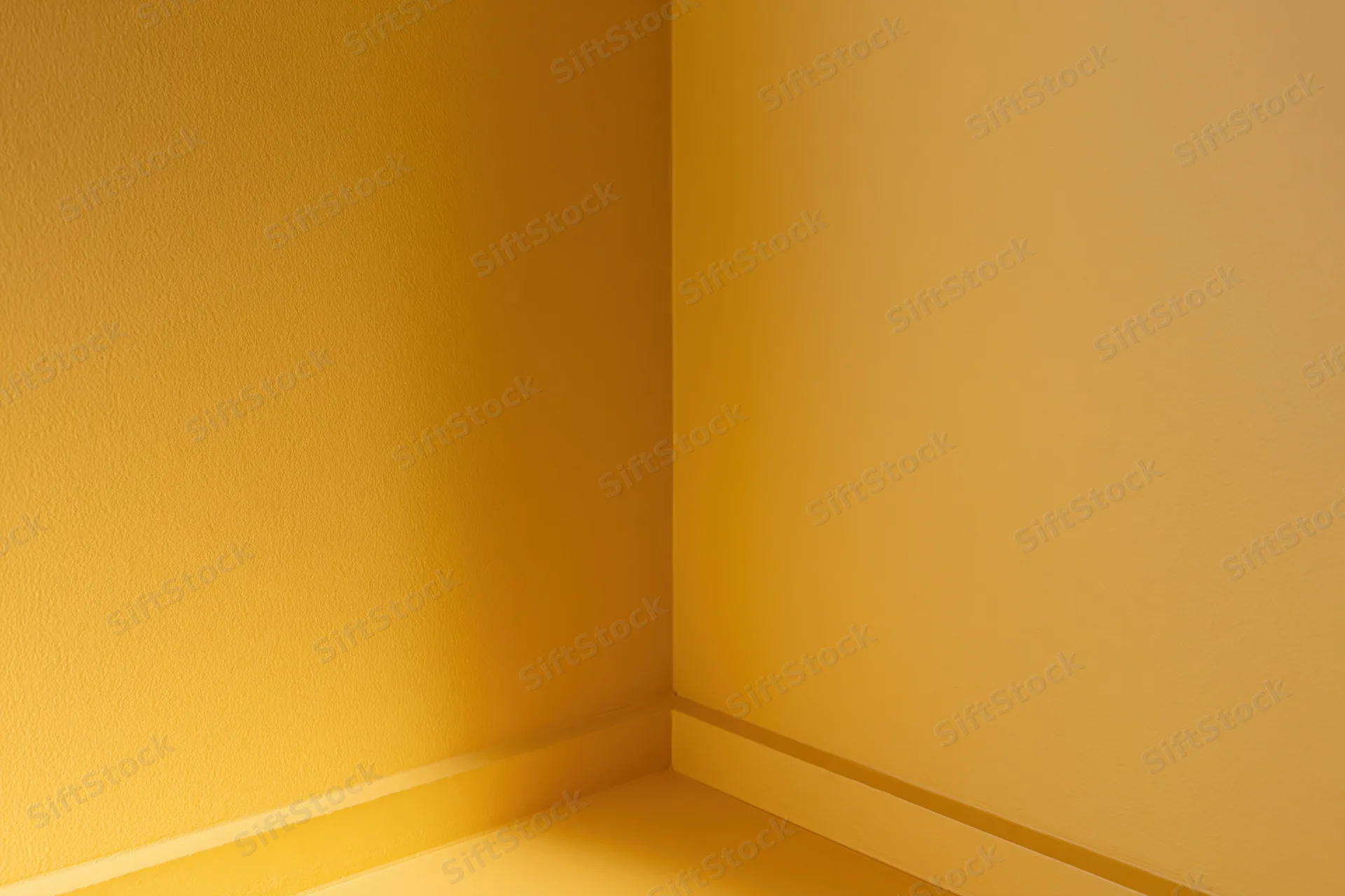Empty corner of a room with golden yellow painted walls and baseboard
