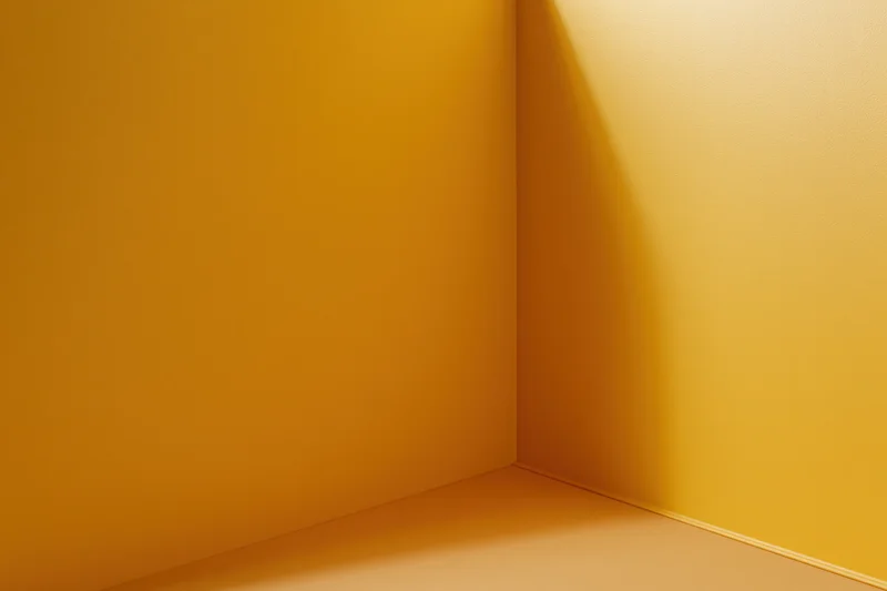 Empty corner of a room with golden yellow walls and floor, casting soft shadow in interior space