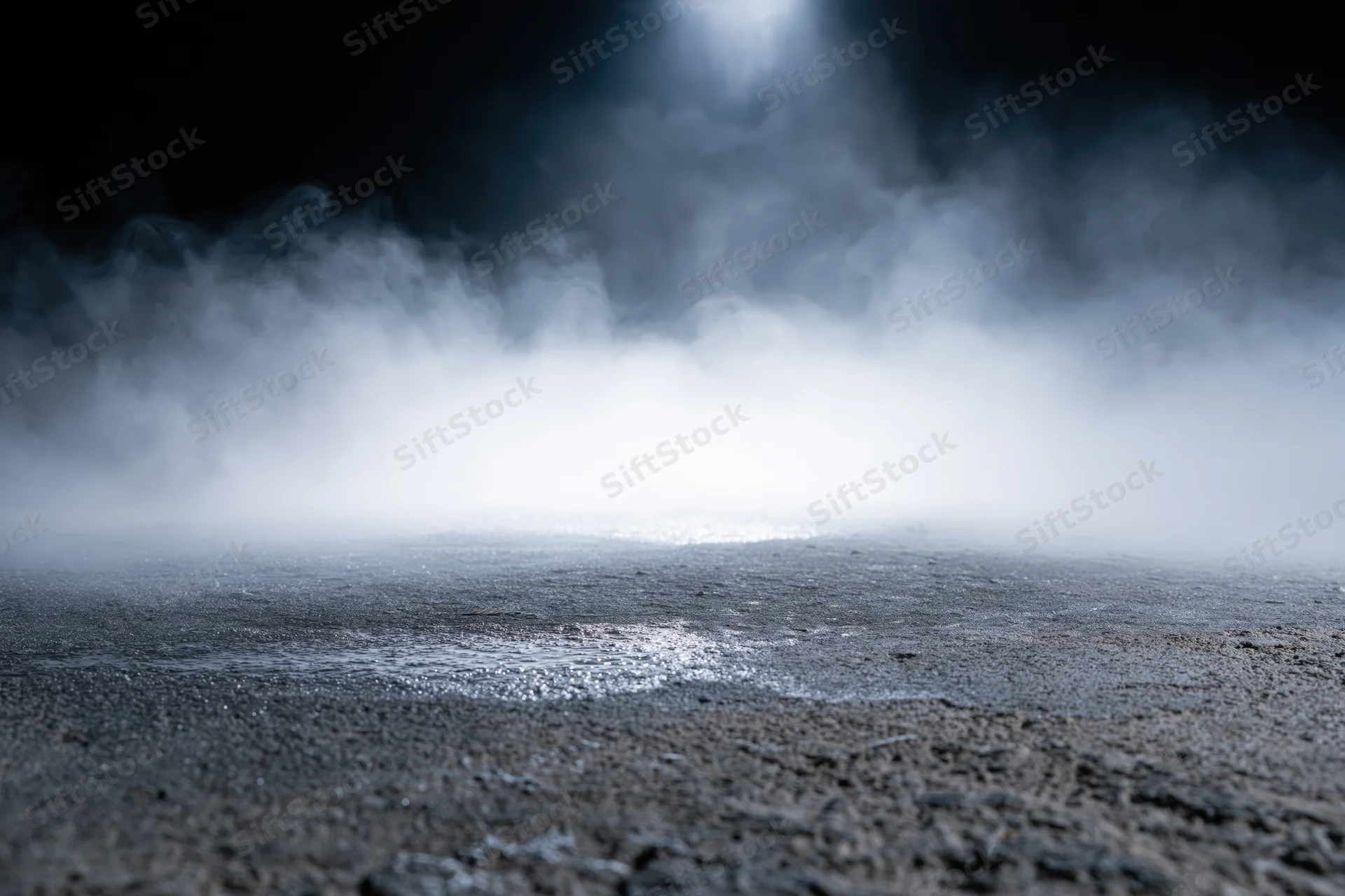 Dense white smoke rising from a dark wet concrete floor at night