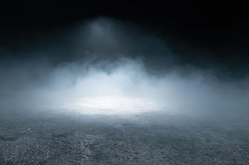 Dark concrete floor with rising white smoke in an empty industrial space