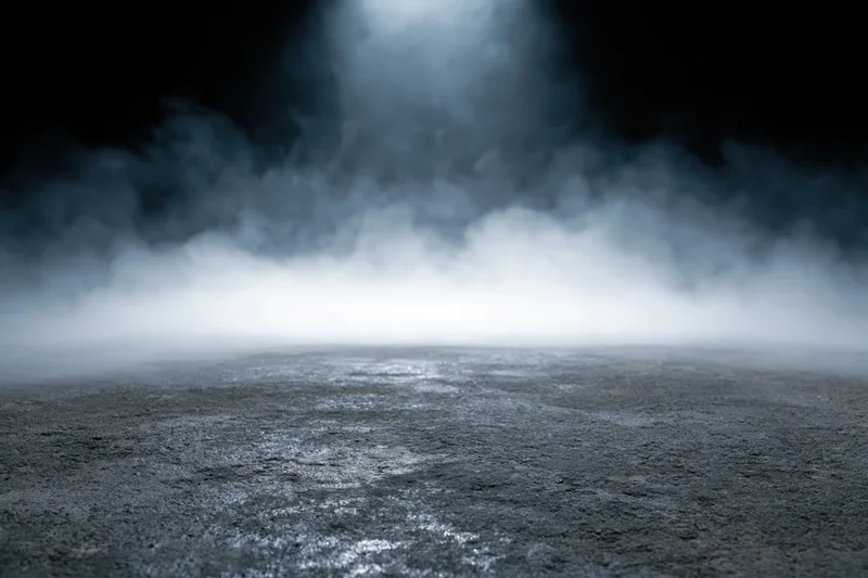 Dark concrete floor with rising white smoke in empty industrial space