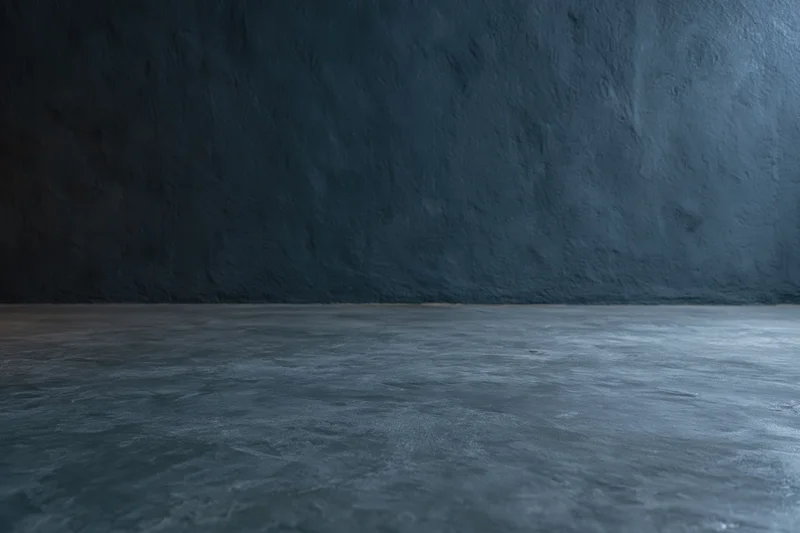 Empty dark concrete room interior with textured wall meeting floor