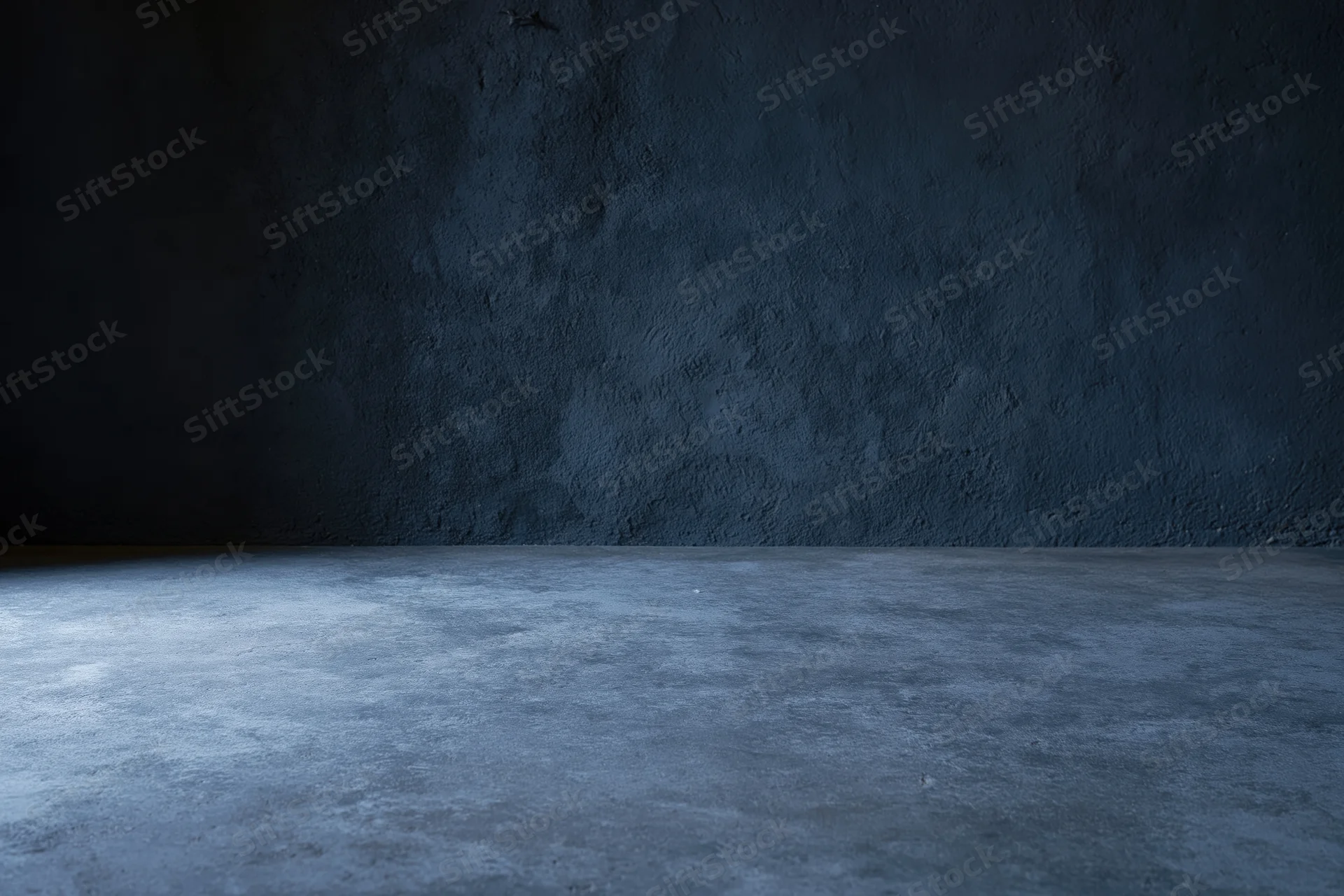 Empty dark concrete room with textured wall and floor meeting at corner